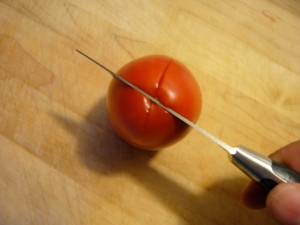 1. Cut an 'X' in the bottom of each tomato with a sharp knife, making sure you cut all the way through the skin