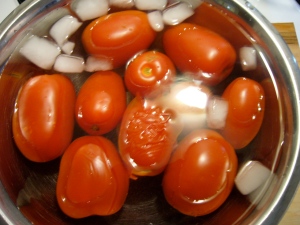 3. Using a slotted spoon, remove tomatoes from boiling water and place them immediately into ice water