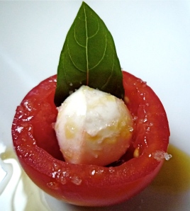 A cocktail tomato stuffed with fresh mozzarella and a basil leaf